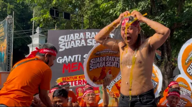 Aksi salah satu peternak mandi telur dengan memecahkan telur mentah di bagian kepala dan badan saat menggelar aksi demo di Bundaran Gladak, Solo, Selasa (7/7)