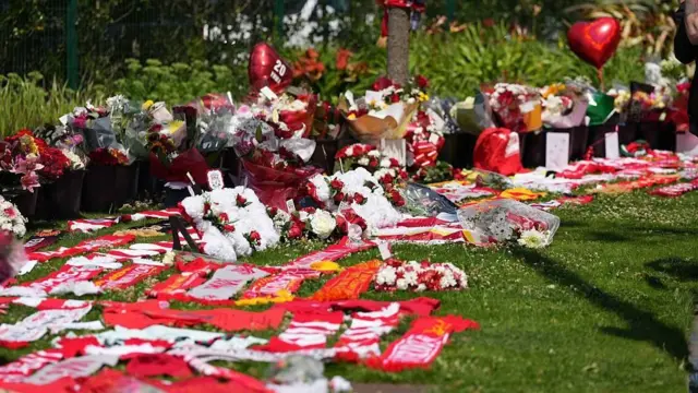 芝生の上に、花や風船などが並べて置かれている