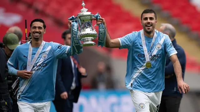 Tijjani Reinders and Rodri holding the FA Cup trophy