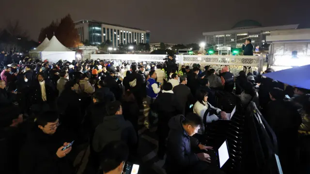 La puerta principal de la Asamblea Nacional en Seúl abarrotada de gente mientras la policía bloquea la entrada tras la declaración de la ley marcial por parte del presidente Yoon Suk-yeol el 3 de diciembre de 2024.