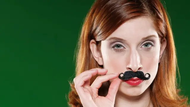 Une jeune fille appliquant une fausse moustache