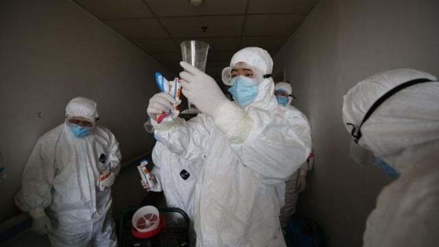 Chineses com roupa de proteção em hospital