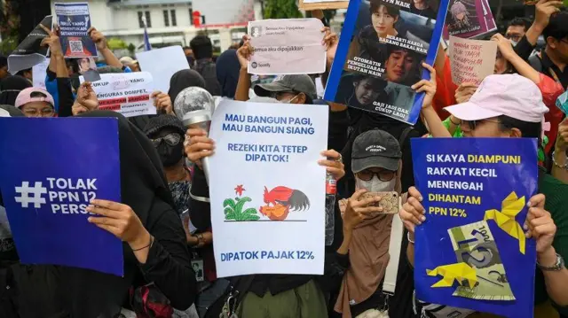 Sejumlah pengunjuk rasa membawa poster saat aksi penolakan PPN 12 persen di depan Istana Merdeka, Jakarta, Kamis (19/12).