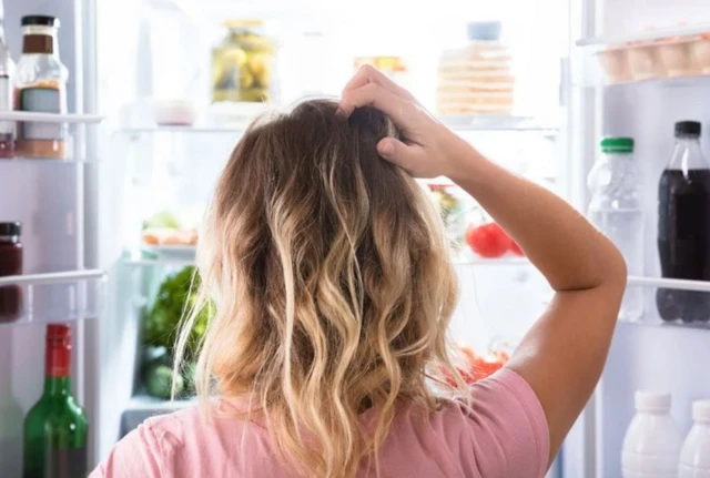 รูปผู้หญิงเกาหัวยืนเปิดตู้เย็น