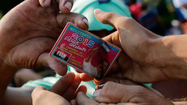 Antiguos simpatizantes sandinistas tratan de quemar su carnet de militantes del FSLN.