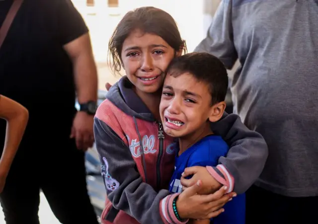 Menina e menino palestinos choram abraçados