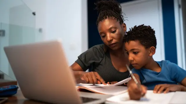 Menino estudando ao lado da mãe