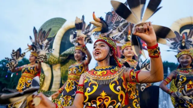 鳥を模した頭飾りをつけ、両手に羽を持った女性ダンサーが躍っている