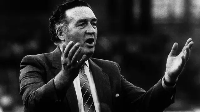 Foto em preto e branco de Jock Stein com os braços erguidos