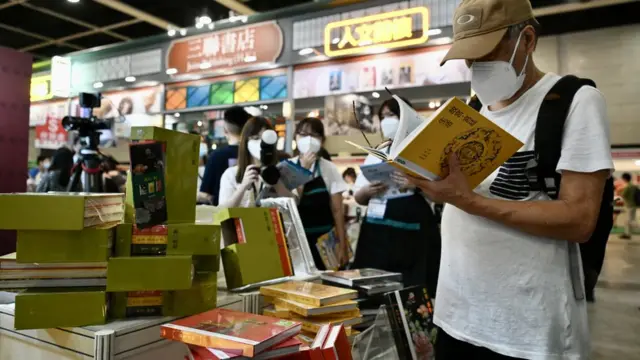 香港書展一書攤上一位讀者翻閲有關北京故宮的書籍(中新社圖片20/7/2022)