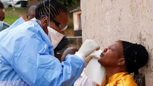 A health worker wearing a protective suit takes a swab from a resident during a door-to-door testing