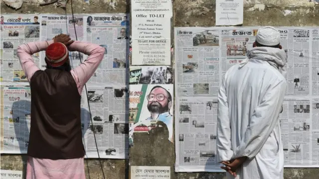 ঢাকায় একজন দেয়ালে সাঁটানো পত্রিকা পড়ছেন, ২৯/১২/২০১৮