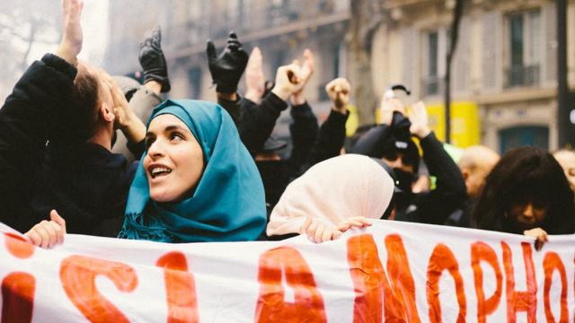 Mulher de lenço segura carta contra islamofobia em protesto na França em 2009