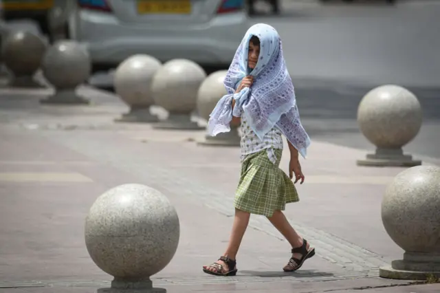 डोक्याभोवती स्कार्फ घेऊन चालणारी मुलगी