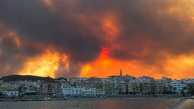 El fuego resplandece detrás de una ciudad costera en Andalucía.