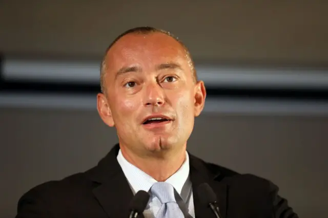 Bulgarian politician Nickolay Mladenov speaking into a microphone while dressed in black suit and pale blue tie. 