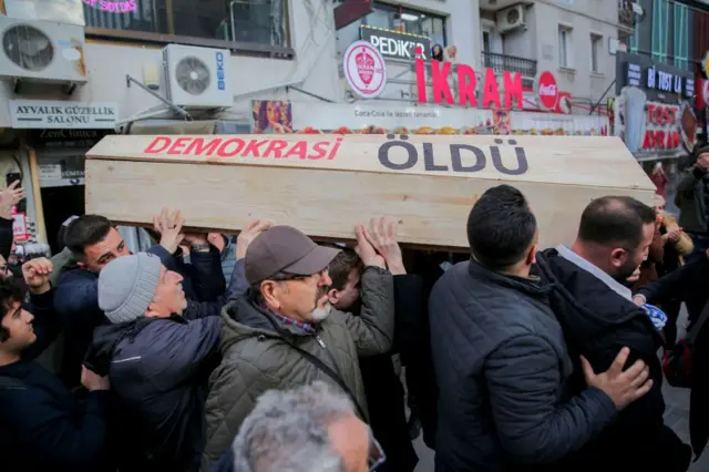 20 Mart 2025 tarihinde İzmir'de düzenlenen protesto sırasında Ekrem İmamoğlu'nun gözaltına alınmasını eleştiren göstericileri üzerinde “Demokrasi öldü” yazan sembolik bir tabut taşıdı.