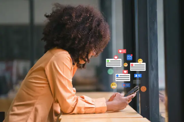 ቁጭ ብላ የማኅበራዊ ሚዲያ ላይ የተሰጡ አስተያየቶችን የምታይ ሴት