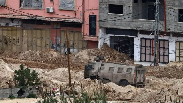 مركبة إسرائيلية في طريق مدمر في مخيم نور شمس بسبب المداهمات الإسرائيلية. الصورة التقطت نهاراً