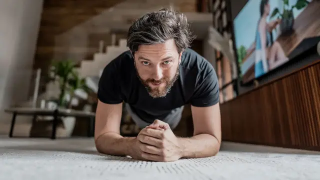 Чоловік стоїть у планці та дивиться в камеру