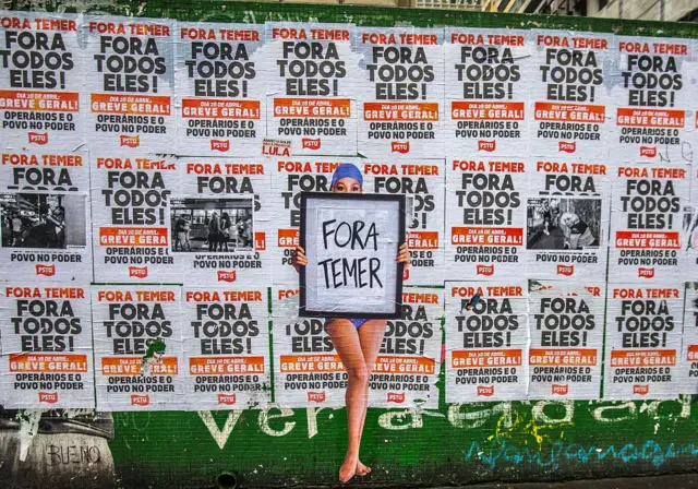 Una obra de arte urbano realizada con la técnica de engrudo (wheat-paste) por el artista Luis Bueno, que representa a un bañista sosteniendo un cartel con la frase «Fuera Temer», en la Avenida Paulista, el 19 de mayo de 2017 en São Paulo, Brasil.