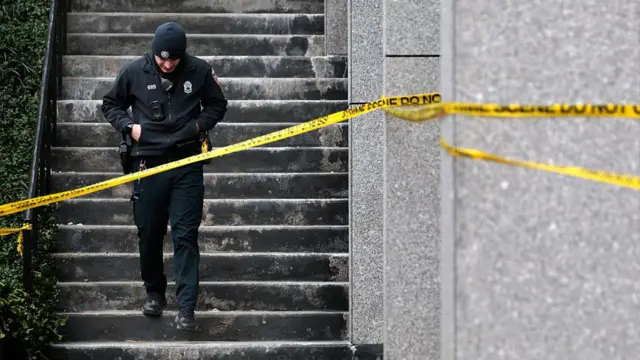 Brown Üniversitesi saldırısından sonra bir polis güvenlik şeridinin arkasında yürüyor.