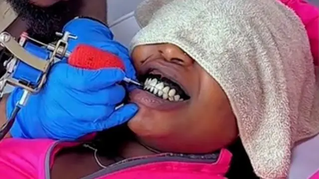 Umugore urimo gukorerwa tattoo yo ku ishinya