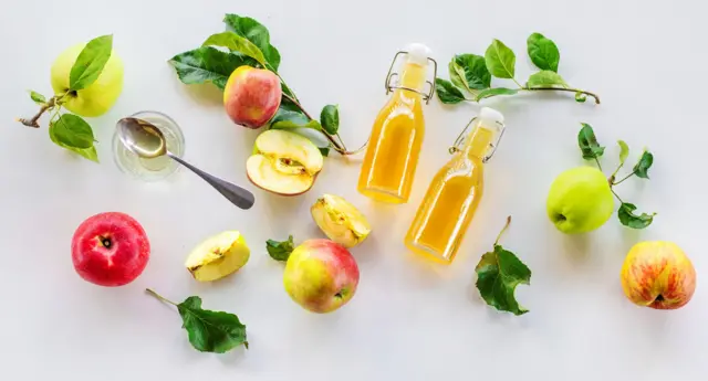 Elma ve elma sirkesi şişeleri yan yana duruyor