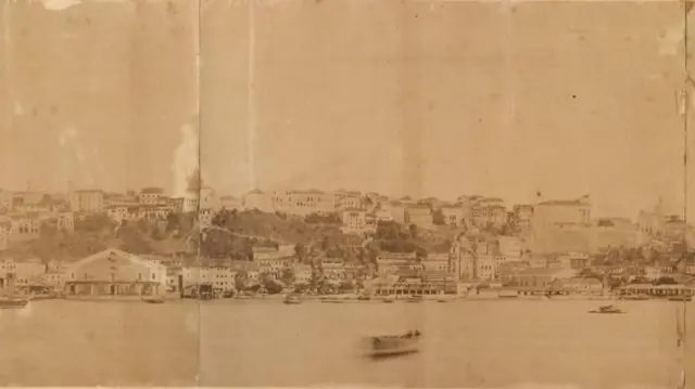 Aparentemente uma fotografia em tom sépia mostra mar e casas de Salvador