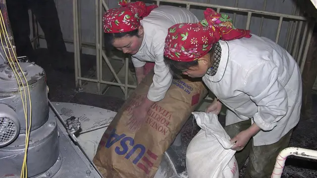 북한 노동자들이 WFP에서 받은 우유 자루를 들고 있다