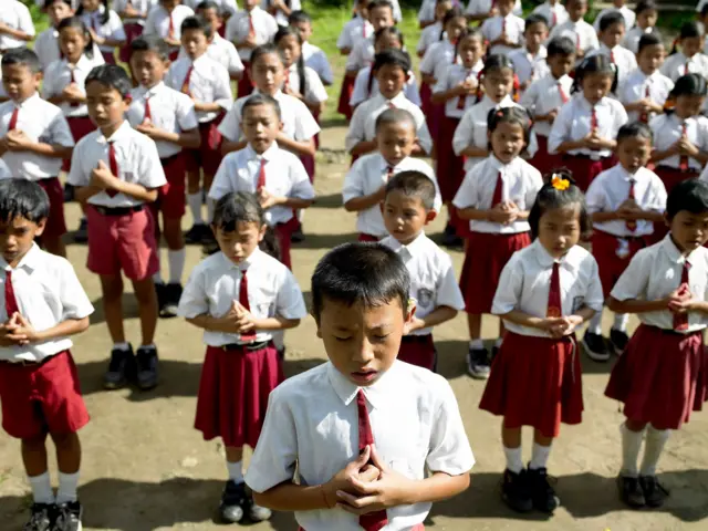 Anak-anak di Sekolah Dasar sedang berdoa bersama di halaman sekolah. 