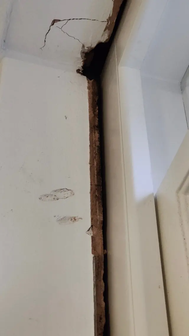El marco de la ventana está mal asentado en la pared y presenta daños en el ladrillo circundante, incluidas grietas.