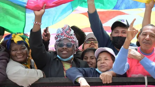 Colombianos sonríen y ondean una bandera multicolor