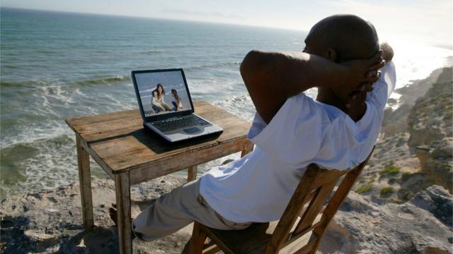 Hombre sentado con una computadora en la playa