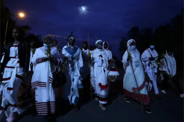 Men and women dressed in white robes walk to attend Irreechaa celebrations.