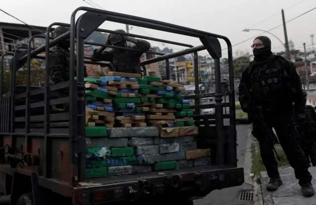 Soldados brasileiros e policiais civis carregam um caminhão com drogas em área da favela de Chatuba durante uma operação contra traficantes no Rio de Janeiro.