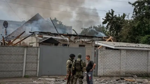 Police officers speak with a local resident as his house burns following shelling, as Russia"s attack on Ukraine continues, in Lysychansk, Luhansk region Ukraine June 2, 202