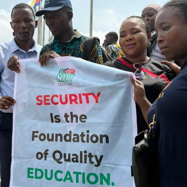 Pesin dey hold banner wey tok say, "Security na di foundation of quality education"