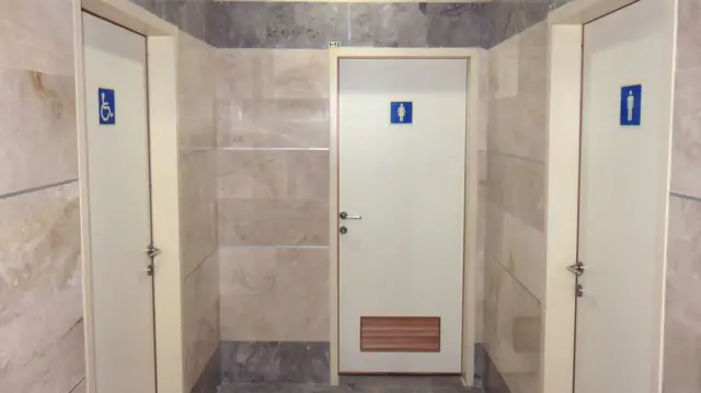 beyaz renkli umumi tuvalet kapıları ve üzerinde cinsiyet ve engelli işaretleri