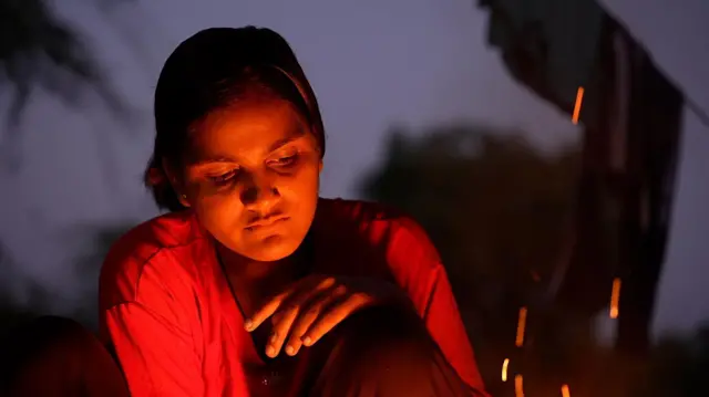 रात में आग के सामने बैठी मुन्ना