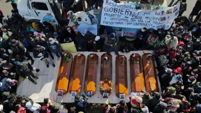 Siete ataúdes son rodeados por dolientes