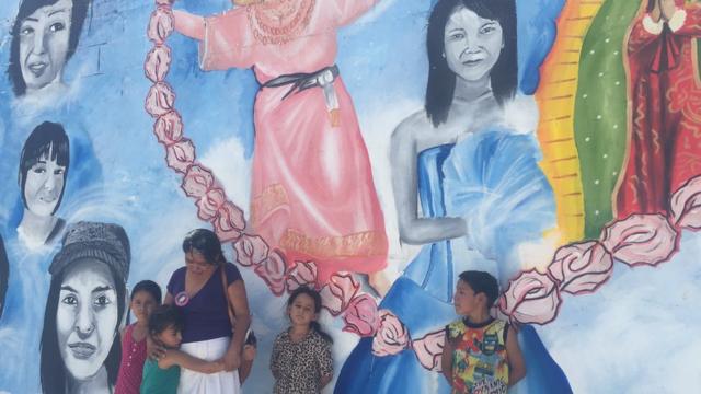 Anita Cuéllar con sus cuatro nietos junto al mural que mandó pintar con la imagen de su hija desaparecida.