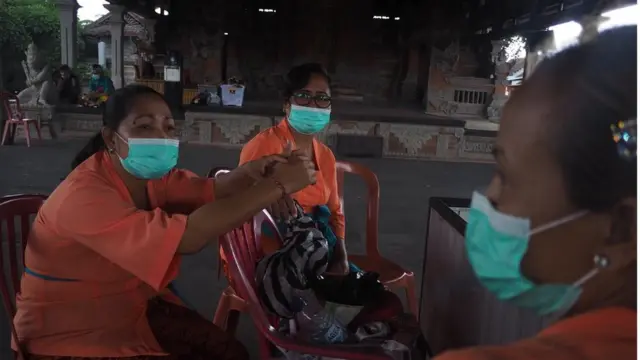 Petugas di Pura Batuan mengenakan masker untuk mengantisipasi penularan virus corona (30/01).