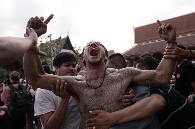 A devotee (C) reacts during the annual magic tattoo festival (Wai Kru festival) at Wat Bang Phra in Nakhon Pathom province, Thailand.