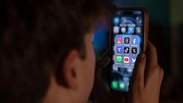 一名少年正在查看iPhone萤幕上显示的各种社群媒体应用程式。