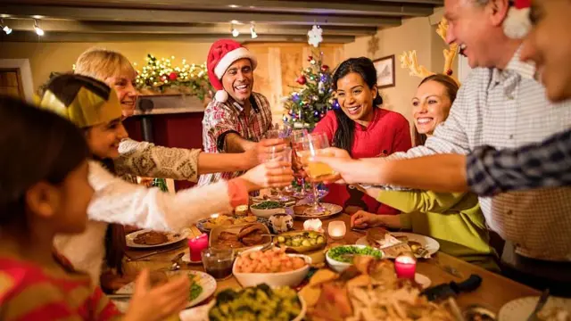 Personas brindando en torno a una mesa durante la Navidad