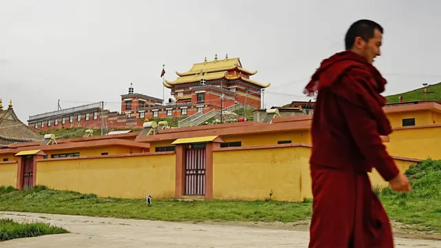 Um monge passa pelo monastério de Langcuo Ma