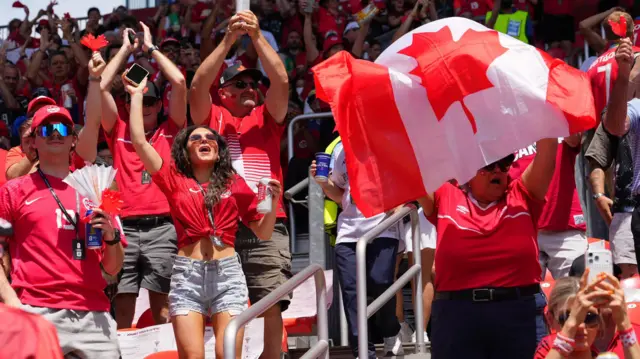 Penggemar Kanada di dalam stadion mengibarkan bendera dan bersorak