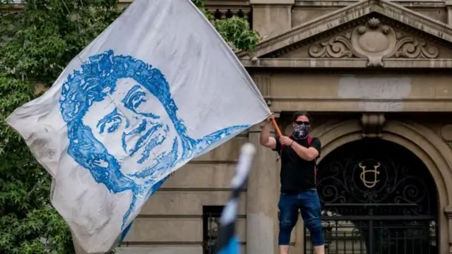 Homem agita uma bandeira com a imagem de Víctor Jara