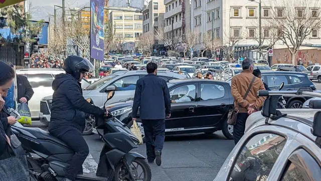 Iraníes intentan despejar una calle en medio del denso tráfico en Teherán,
